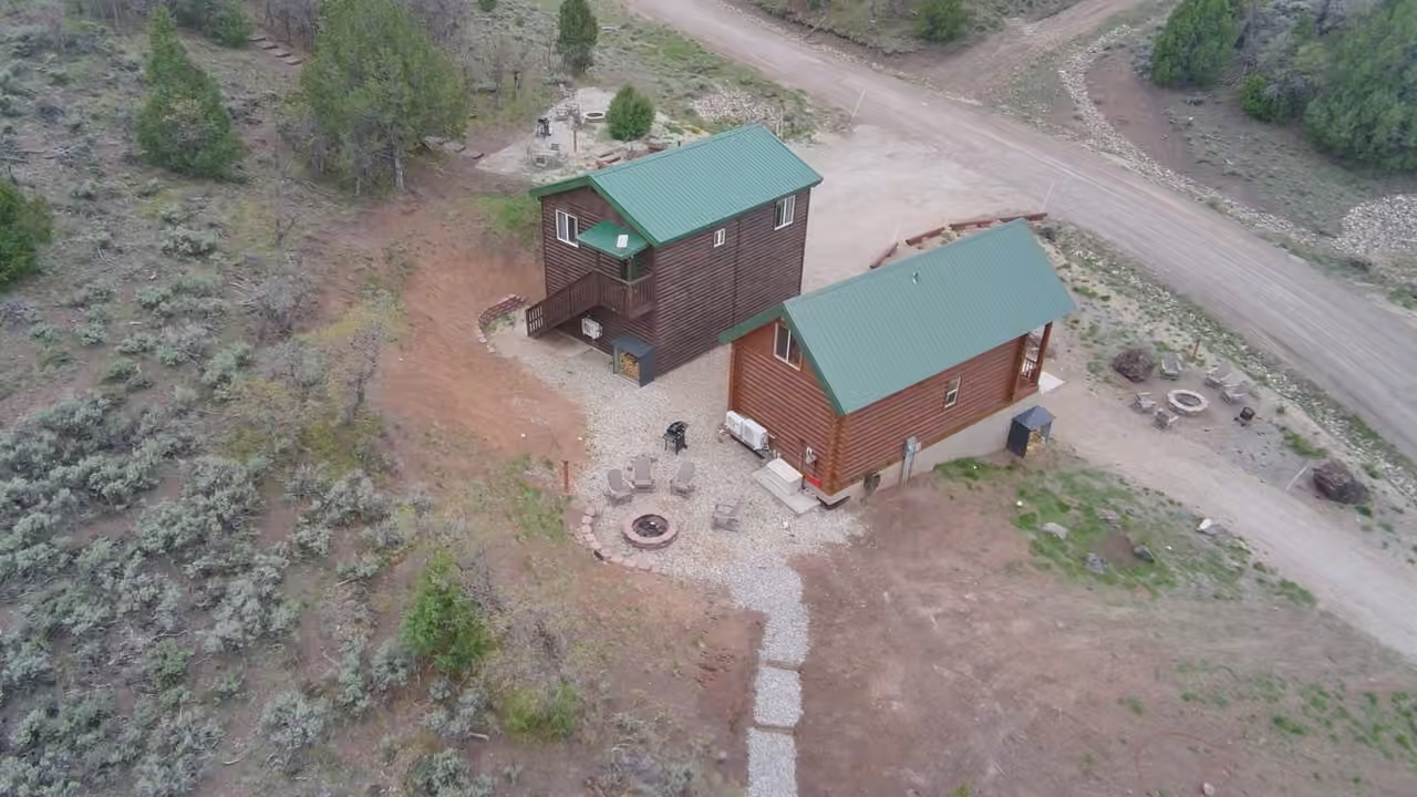Aerial drone view of two Starlit Ridge cabins with fire pits and gravel paths