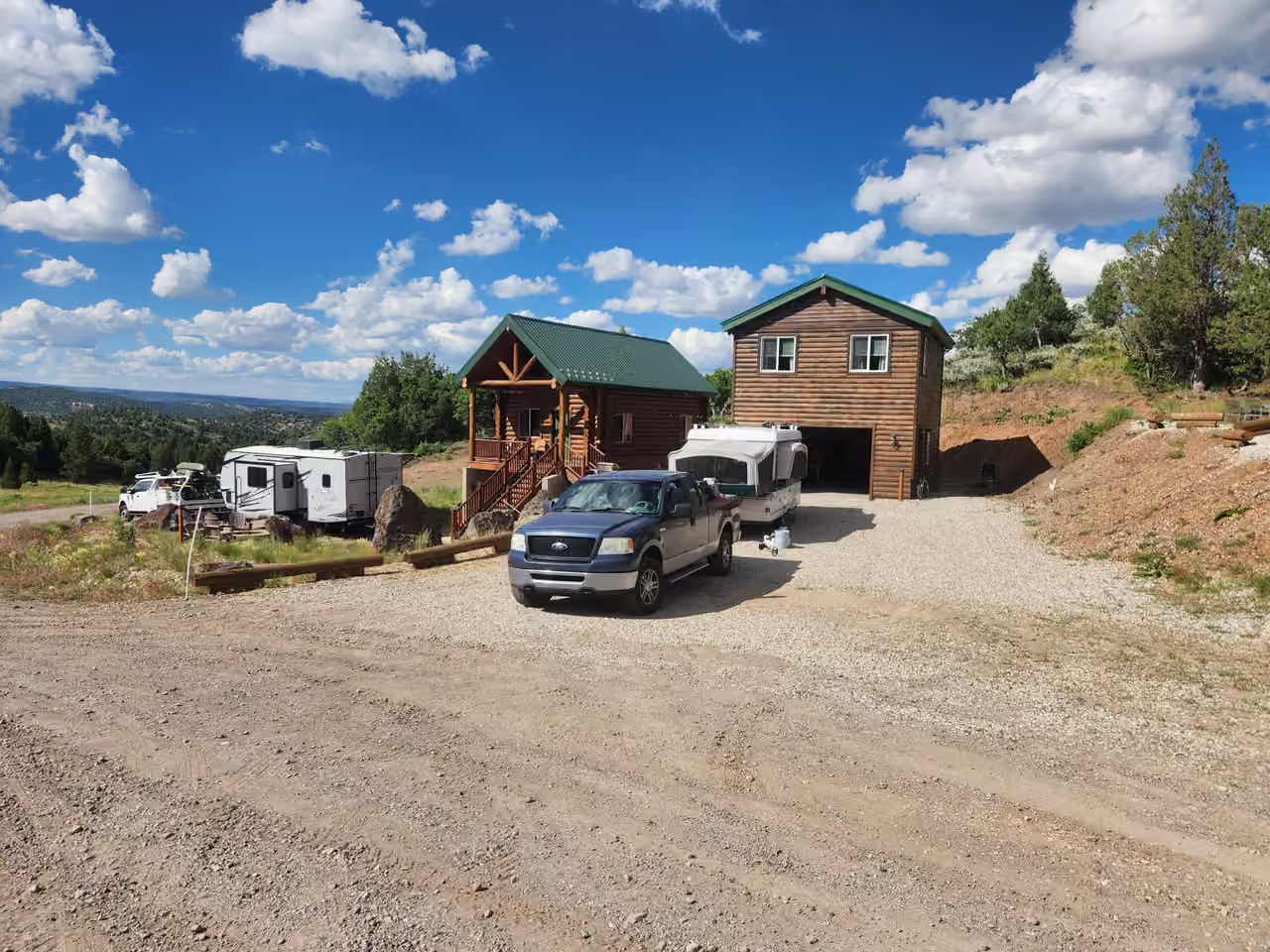 Starlit Ridge cabins with trucks, a travel trailer and a pop-up camper parked out front