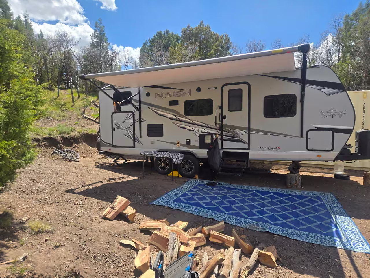 Travel trailer with awning and outdoor rug at a Starlit Ridge campsite