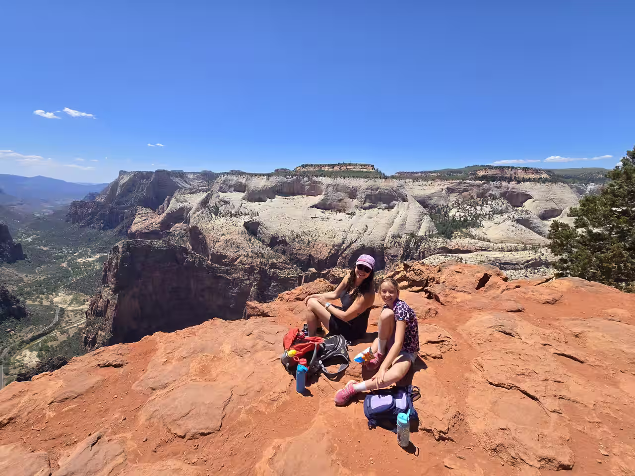 Hikers resting at the Observation Point overlook with Zion Canyon spread out below