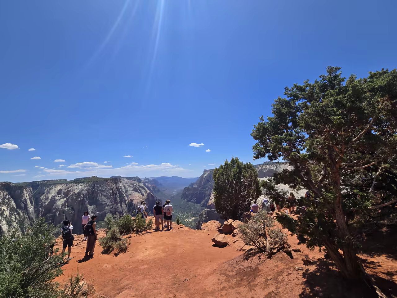 Hikers eating lunch and resting at the Observation Point summit on a busy day